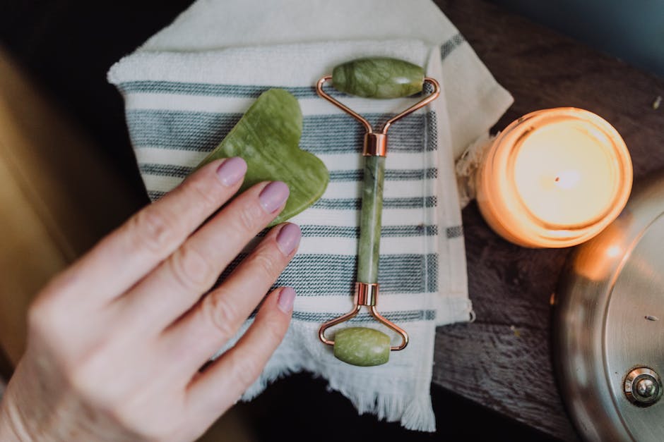 A serene spa setup with a jade roller, heart-shaped stone, and candle for relaxing self-care
