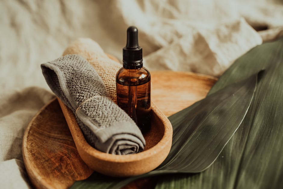 A soothing setup of skincare essentials featuring a dropper bottle, towel, and leafy backdrop, perfect for wellness inspiration