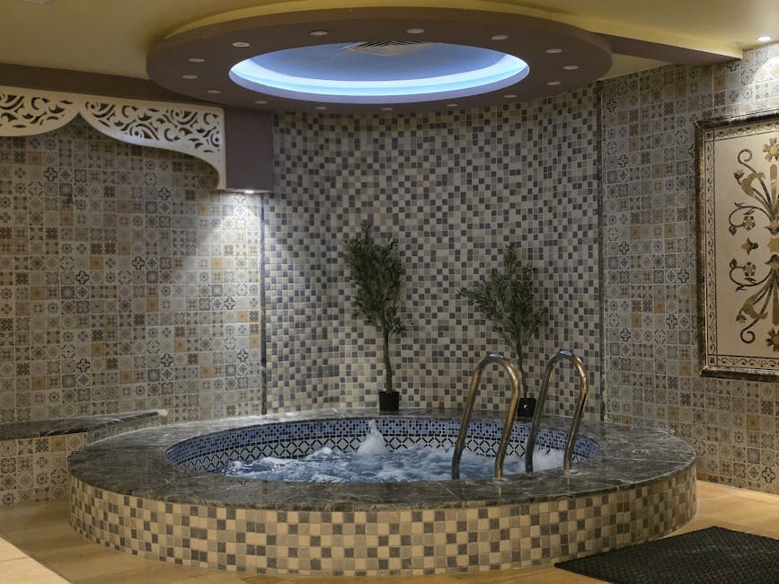 A serene indoor spa setting featuring a mosaic tiled jacuzzi with ambient lighting