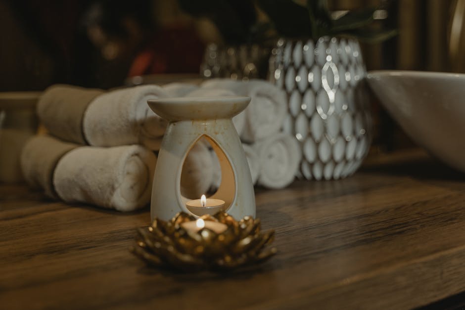 Serene spa setting with a lit candle, ceramic holder, and plush towels for relaxation